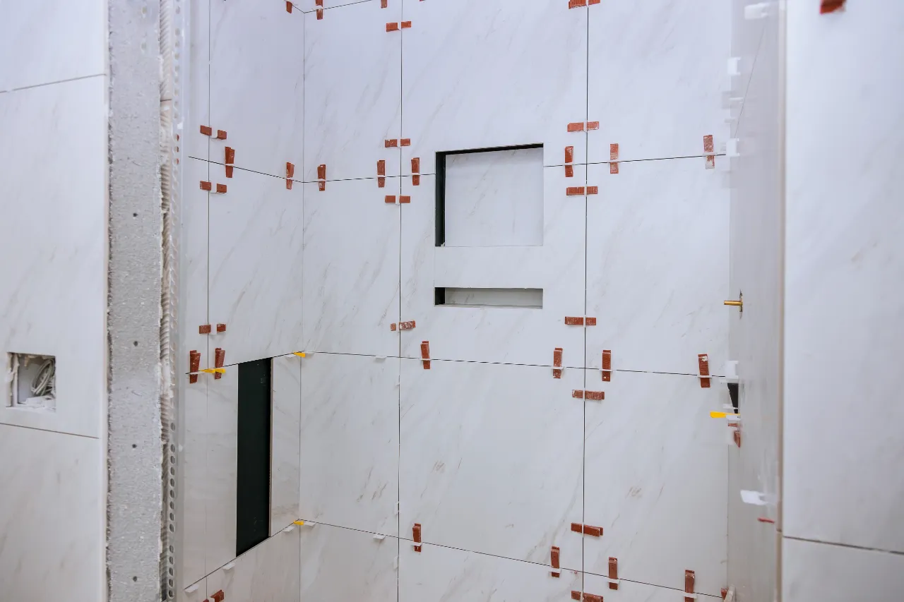 Tile setter placing bathroom wall tile with even spacing