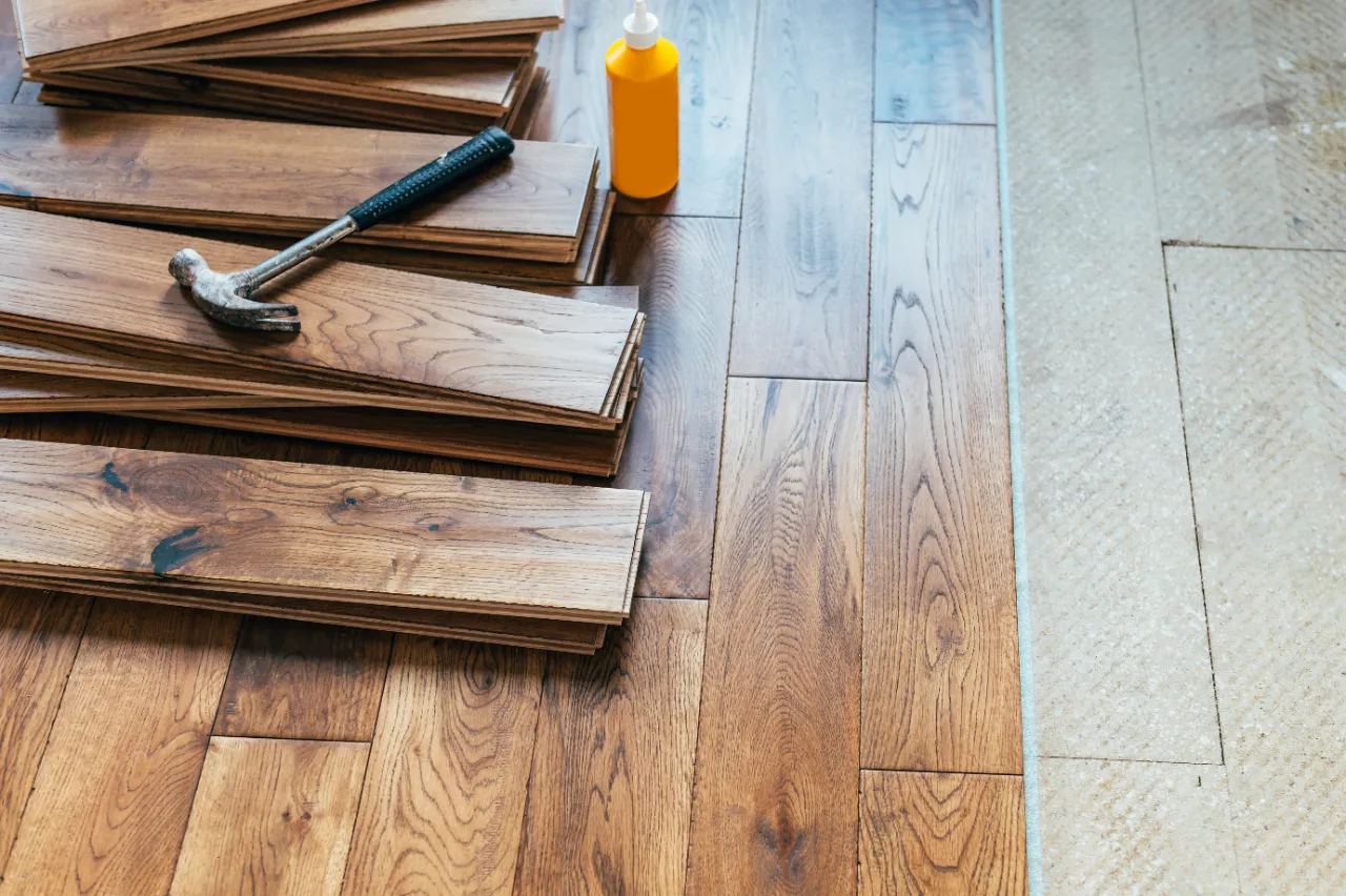 Setting wood flooring with hammer and adhesive in Bridgeport, CT